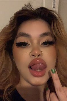 a woman with long hair and nose piercings making a funny face while holding her finger up