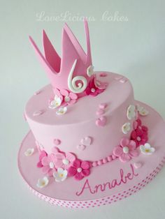 a pink cake decorated with flowers and a crown