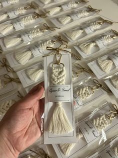 a hand is holding some white yarn in front of many packages with tags on them