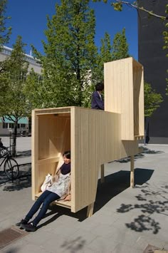 a person sitting in a wooden structure on the sidewalk