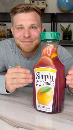 a man sitting at a table with a bottle of fruit juice