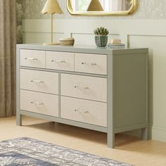 a dresser with two lamps and a mirror above it in a room that has a rug on the floor