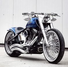 a black and blue motorcycle parked in front of a white garage door with chrome rims