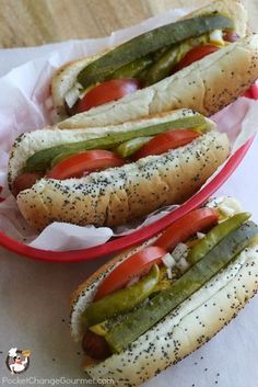 two hot dogs in buns with tomatoes, pickles and relish on them