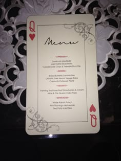 a menu card sitting on top of a lace covered table cloth with red and white designs