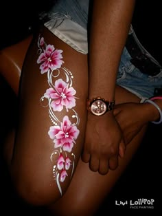 a woman's leg with flowers painted on it and a watch in her hand