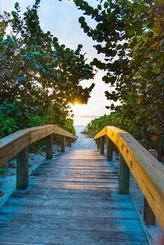 a wooden walkway leading to the beach at sunset