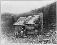 an old black and white photo of two people in front of a cabin