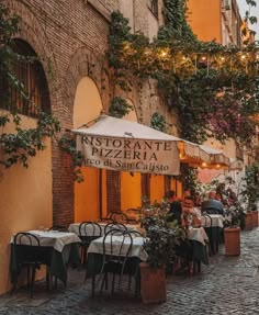 an outdoor restaurant with tables, chairs and umbrellas on the side of a street