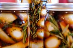 three jars filled with food sitting on top of a table next to each other and sprigs in them