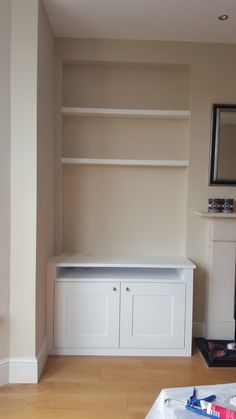 an empty room with some white cabinets and drawers on the wall next to a fireplace