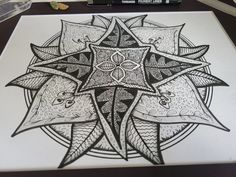 a drawing of a star with intricate designs on it's surface next to markers and pens