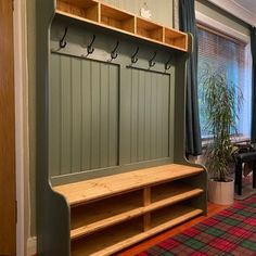 a room with a bench and some plants on the wall next to a window that has blue curtains