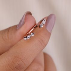 a woman's hand holding a ring with three diamonds on the middle of it