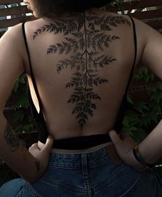 the back of a woman's body with tattoos on her upper and lower back