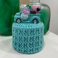 a blue crocheted hat with a pink heart on it and a green bottle in the background