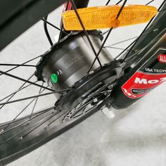 the front wheel of a bicycle with spokes and brake pads on white fabric covered flooring