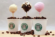 three starbucks cups filled with marshmallows and chocolate covered lollipops