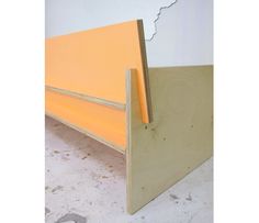 a yellow bed frame sitting on top of a white floor next to a wooden wall