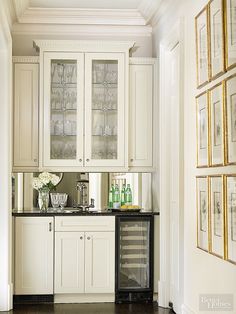 a kitchen with white cabinets and black counter tops in front of pictures on the wall