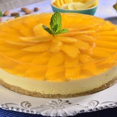 a cheesecake on a plate with some lemons and mint leaves around the edges