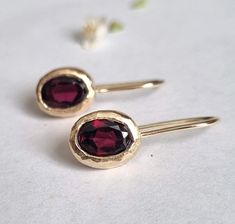 Delicate oval gold drop garnet gemstone earrings, romantic and classic January birthstone jewelry earrings for women available in 14k gold plating, sterling silver, 9k and 14k solid gold. Delicate handmade oval gold earrings set with garnets, with a classic and clean design.  They are available in quality 14k gold plating, sterling silver, 9k yellow solid gold or 14k yellow solid gold. These unique gold earrings are excellent for everyday earrings and special occasions. The garnet gems combine w Oval Garnet Gemstone Earrings, Dainty Silver Earrings, Gem Drop Earrings, January Birthstone Jewelry, Garnet And Gold, Oval Earrings, Earrings Gemstone, Oval Earring, January Birthstone