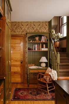 a room with a chair, bookshelf and rug on the floor in front of it