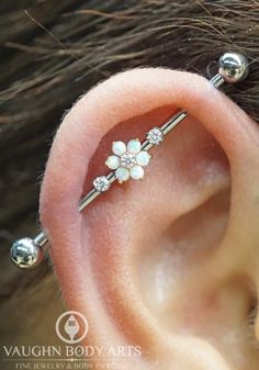 a close up of a person's ear with a flower on it and two piercings