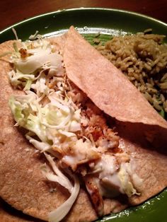 a green plate topped with two tacos and rice