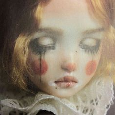 a close up of a doll's face with blood on her eyes and nose