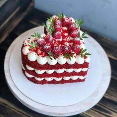 a piece of red velvet cake with white frosting and berries on top sits on a plate