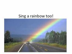 a car driving down the road with a rainbow in the sky and trees behind it