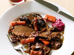 a white plate topped with meat and veggies on top of a wooden table