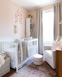 a baby's room with pink walls and white furniture