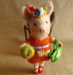 a small stuffed animal with an orange dress and flowered hat holding two green apples