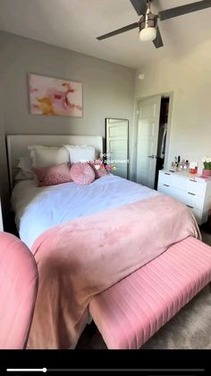 a bedroom with a bed, dresser and ceiling fan in the corner that is pink