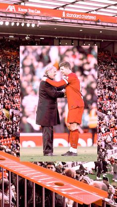 an image of two men hugging each other in front of a crowd at a soccer game