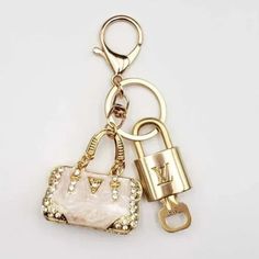 a gold keychain with a white purse on it and a lock attached to it