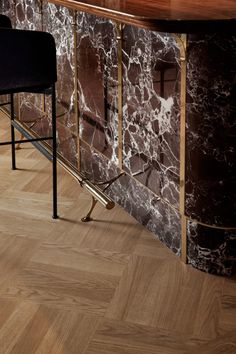 an elegant bar with marble walls and wooden flooring, along with two black chairs