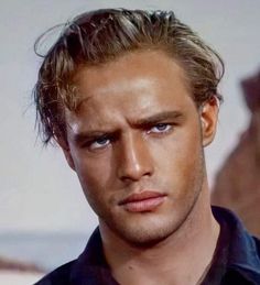 a close up of a person wearing a black shirt and looking at the camera with a serious look on his face