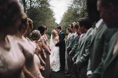 a group of people standing next to each other on top of a road with trees in the background