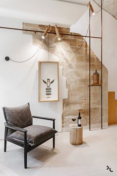 a chair sitting in front of a brick wall next to a wooden table and lamp