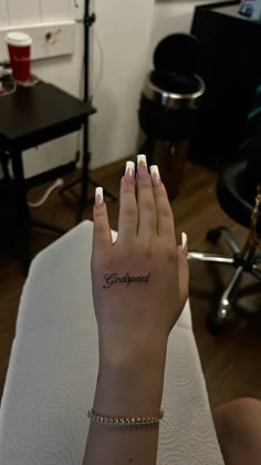 a woman's hand with a small tattoo on her left wrist and the word godpared written in cursive writing