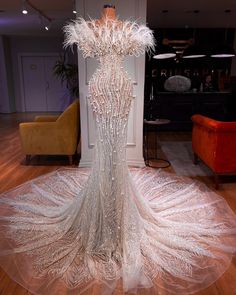 a dress made out of feathers on display in a room with chairs and couches