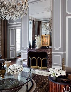 a living room filled with furniture and a chandelier hanging from the ceiling over a fire place