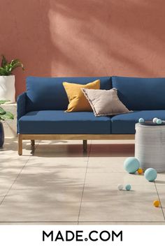 a blue couch sitting on top of a tiled floor next to a potted plant