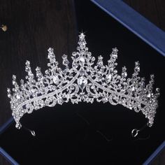 a tiara is displayed on a black surface in front of a blue box with flowers