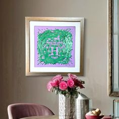 a vase with pink flowers sitting on top of a wooden table next to a mirror