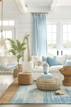 a living room filled with lots of white furniture and blue curtains on the windowsill