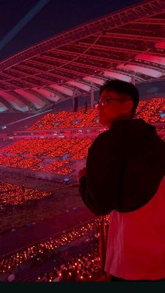 a man standing in front of a stadium filled with red lights